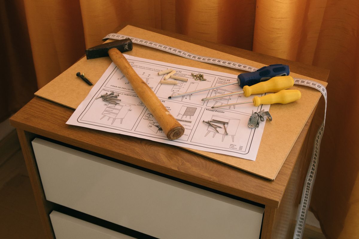 Outils et notice de montage posés sur un meuble en bois.