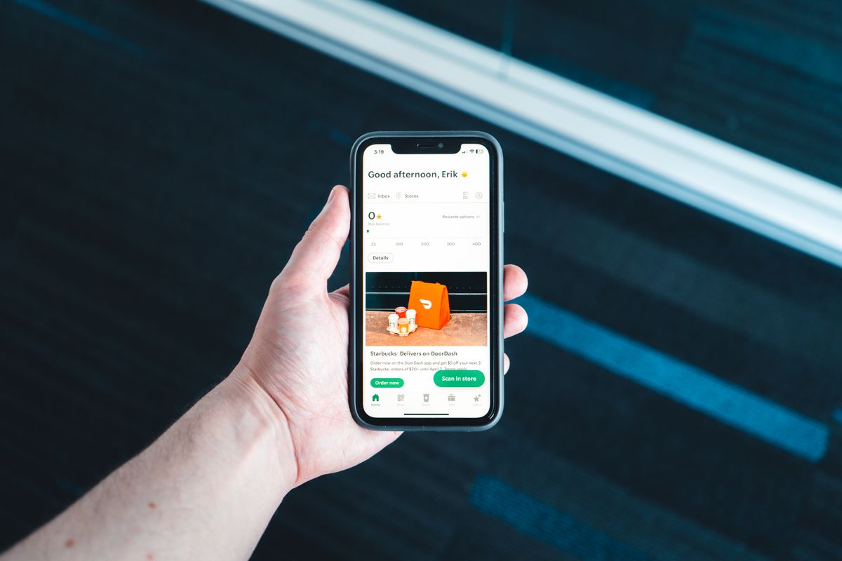 Main tenant un smartphone affichant une application de livraison.